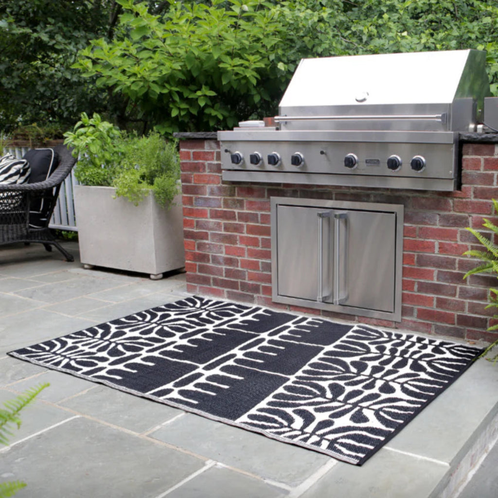 Outdoor patio with a grill and decorative black and white patterned rug